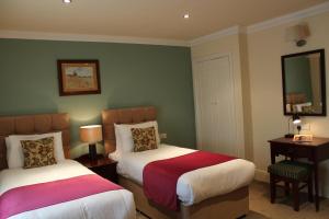a hotel room with two beds and a mirror at The Dibbinsdale Inn in Bromborough