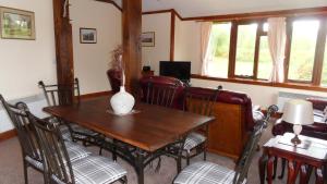 a dining room table with chairs and a vase on it at Meadowside Cottages in Balavil