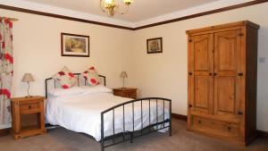 a bedroom with a bed and a wooden cabinet at Meadowside Cottages in Balavil