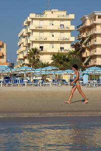 una donna che cammina sulla spiaggia vicino a un hotel di Hotel Bahia a San Benedetto del Tronto