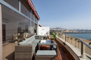 - un balcon avec des canapés et une table dans un bâtiment dans l'établissement Living Las Canteras Homes - PENTHOUSE FREE PARKING, à Las Palmas de Gran Canaria