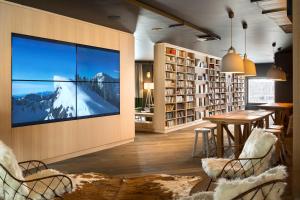 a living room with a large screen tv on the wall at Araucaria Hotel & Spa in La Plagne