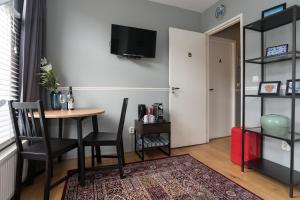 uma sala de estar com uma mesa e cadeiras e uma televisão em Westerpark Home em Amsterdã