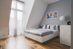 a white bedroom with a bed and a large window at Living Apartments Poznań in Poznań