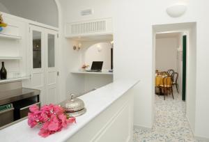 ラヴェッロにあるイル ドゥカート ディ ラベッロ ホテルの白いキャビネットとピンクの花が並ぶカウンター付きのキッチン