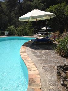 una piscina con sombrilla y silla en la maison bleue en Carros