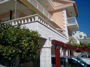 a white house with a balcony and a car parked in front at Apartments Jani in Hvar