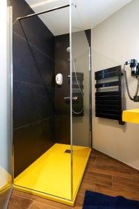 a glass shower with a yellow floor in a bathroom at Logis Hôtel La Chaize in Noirmoutier-en-l'lle