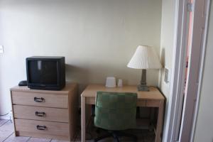a desk with a television and a green chair at Budget Inn in El Cerrito