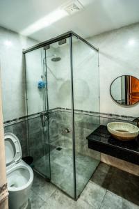 a bathroom with a glass shower and a toilet at Homestay Villa Full House in Ha Long