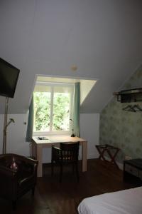 a room with a table and a window and a desk at Hotel De Hoefpoort in Gemert