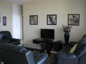 sala de estar con 2 sillas de cuero y TV en Colonial Sands B, en Margate