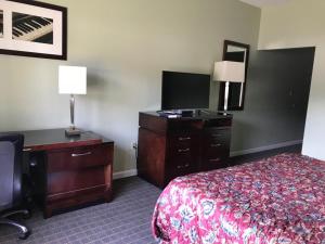 a hotel room with a bed and a dresser and a desk at CCI Express Inn in Central City