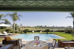 a patio with a table and chairs and a swimming pool at Villa MEZIANE avec piscine privée en première ligne du golf d'Amelkis in Marrakesh