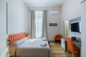 a bedroom with a bed and a desk and a television at VRooms All'Angolo Del Duomo in Florence