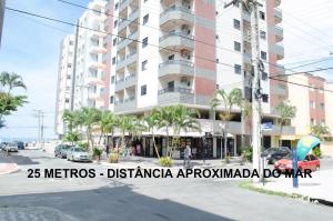 a building on a city street with palm trees at CONFORTO IMBATIVEL - 25 metros do MAR - 2 Quartos com AR CONDICIONADOS SPLIT, Air Fryer, WI-FI, Disney Plus, Star Plus, HBO Max, Cadeiras de Praia e Caixa Térmica - 8 pessoas com Muito Conforto - Melhor Localização! in Guarapari