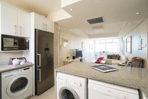 a kitchen with a washer and dryer in a room at Sea La Vie Umhlanga - Direct Beach Access by WhereToGo in Durban
