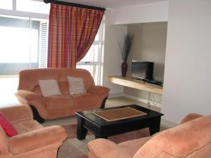 uma sala de estar com um sofá e uma cadeira e uma televisão em La Mer A em Margate
