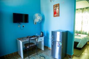 a blue room with a desk and a refrigerator at Asmorein Hotel in Babati
