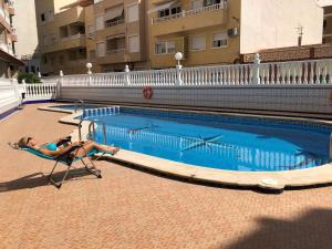 a woman laying in a chair next to a swimming pool at Fresa Apartaments in La Mata