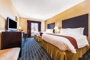 a hotel room with two beds and a flat screen tv at Days Inn & Suites by Wyndham Mineral Wells in Mineral Wells +33 photos