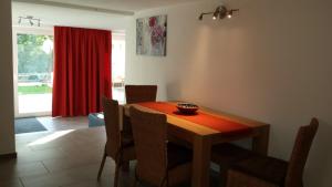 a dining room with a table with chairs and a red curtain at Ferienwohnung Valentin in Hohenpeißenberg +4 photos