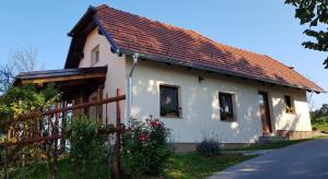 una casa bianca con un tetto rosso e una recinzione di Apartma Lipek a Pristava