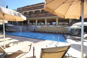 a swimming pool with chairs and umbrellas next to a building at Villa Angela in Taormina