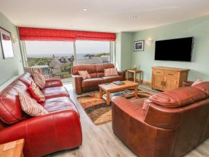 a living room with leather furniture and a flat screen tv at Harmon Vale in Solva
