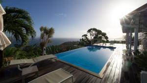 a swimming pool with chairs and the ocean in the background at Villa Cajou chambres d'hôtes chez l'habitant et Zanzibar cottage in Trois-Rivières