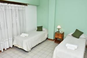 Habitación con 2 camas y mesa con lámpara. en Hotel 30 de Octubre en Mar del Plata