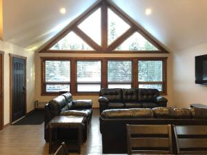a living room with leather furniture and a large window at Wolf Den in Valemount