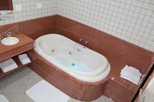 y baño con bañera y lavamanos. en Hotel Dom Henrique, en Timóteo