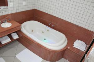 a bath tub in a bathroom with a sink at Hotel Dom Henrique in Timóteo