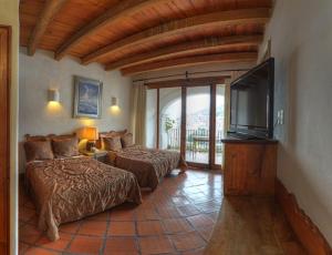 a bedroom with two beds and a flat screen tv at Posada de la Mision, Hotel Museo y Jardin in Taxco de Alarcón