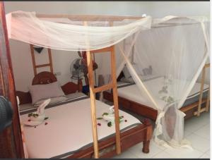 - łóżko piętrowe z baldachimem w pokoju w obiekcie Ebony & Ivory Beach Bungalows w mieście Nungwi