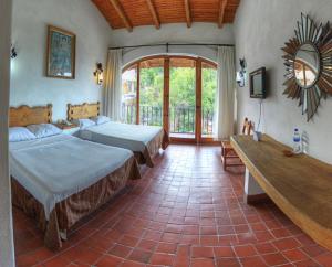 a bedroom with two beds and a large window at Posada de la Mision, Hotel Museo y Jardin in Taxco de Alarcón