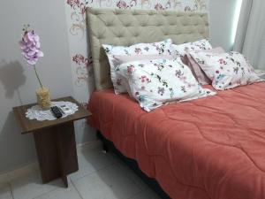 a bed with pink and white pillows and a table at Suítes Pezzin in Paragominas
