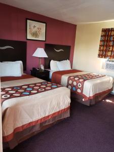 2 łóżka w pokoju hotelowym z czerwonymi ścianami w obiekcie American Inn w mieście Sedalia