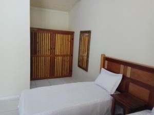 a bedroom with a white bed and a wooden headboard at Pousada Viajantes do Tempo in Cunha