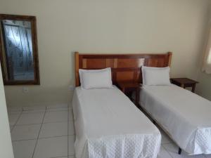 two beds in a room with a mirror at Pousada Viajantes do Tempo in Cunha