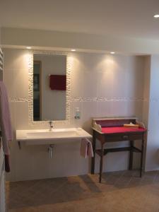 a bathroom with a sink and a mirror and a table at B&B Les Secrets de Tifayne in Puisseguin