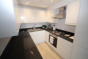una cucina bianca con lavandino e piano cottura di Holden Court Apartments - Apt 3 a West Drayton