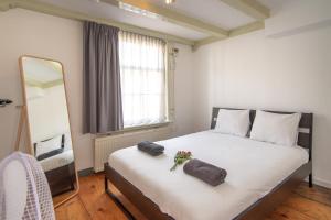1 dormitorio con 1 cama blanca grande y espejo en Spacious Central City Apartment with big private Sundeck!, en Ámsterdam