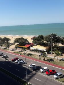 een weg met auto's geparkeerd op een parkeerplaats naast een strand bij Praia de Itaparica Ed Green Diamond Vila Velha ES in Itaparica