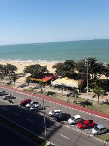 a road with cars parked in a parking lot next to a beach at Praia de Itaparica Ed Green Diamond Vila Velha ES in Itaparica