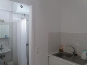 y baño blanco con lavabo y ducha. en Bizas Rooms & Studios, en Parikia