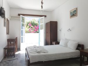 una camera bianca con un letto e una finestra di Bizas Rooms & Studios a Paroikia