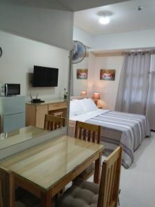 - une chambre avec un lit, une table et une télévision dans l'établissement 101 Newport Blvd Condotel, à Manille