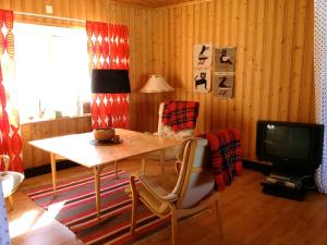 un soggiorno con un tavolo e una televisione di Stora Björnstugan a Laisvall